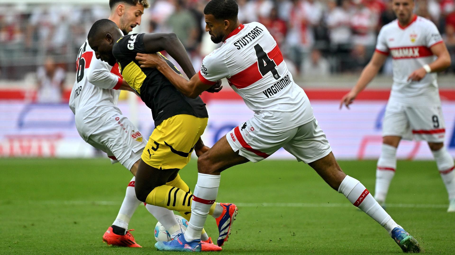 Serhou Guirassy von Borussia Dortmund (M) im Zweikampf mit Stuttgarts Josha Vagnoman (r) und Atakan Karazor. Serhou Guirassy von Borussia Dortmund (M) im Zweikampf mit Stuttgarts Josha Vagnoman (r) und Atakan Karazor.