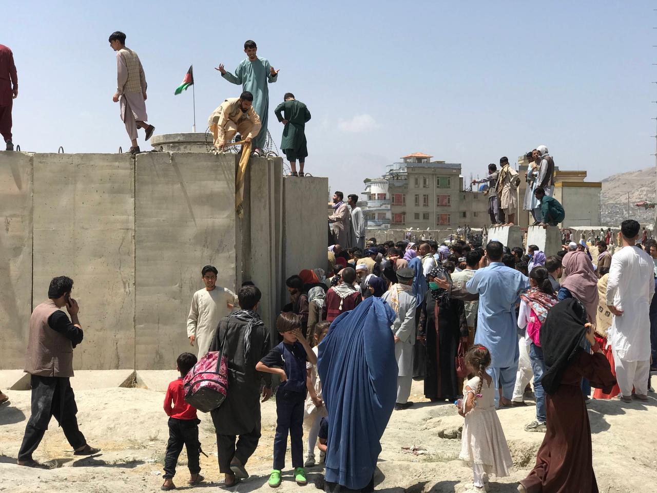 Menschen erklimmen die Mauer um den Kabuler Flughafen.