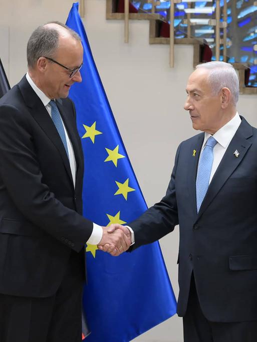 Friedrich Merz und Benjamin Nethanjahu stehen vor der deutschen und der israelischen Flagge und geben sich die Hand. Friedrich Merz und Benjamin Nethanjahu stehen vor der deutschen und der israelischen Flagge und geben sich die Hand.