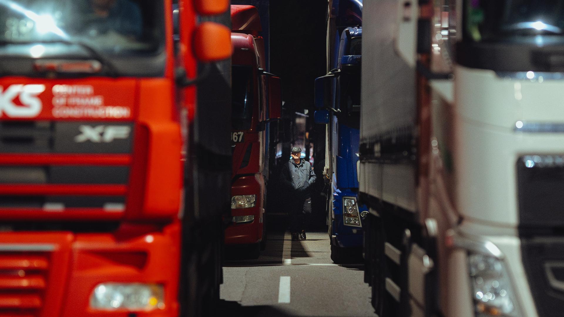 Zahlreiche Lastwagen stehen hintereinander, in der Mitte ist ein Fahrer zu sehen.
