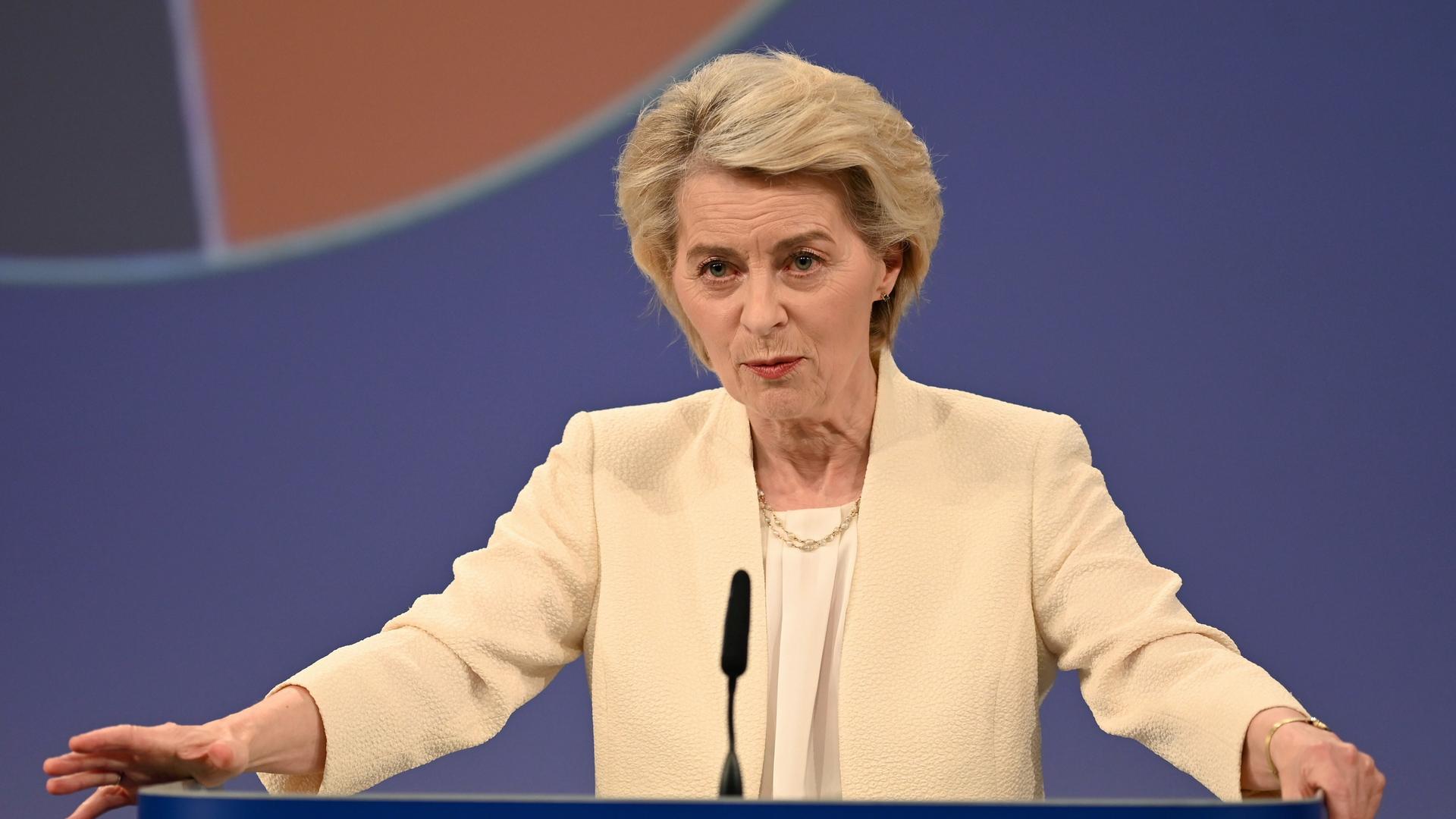 Ursula von der Leyen an einem Redner-Pult. Sie hat die Hände an beiden Seiten von dem Pult aufgestützt. Sie schaut ernst. Ursula von der Leyen an einem Redner-Pult. Sie hat die Hände an beiden Seiten von dem Pult aufgestützt. Sie schaut ernst.
