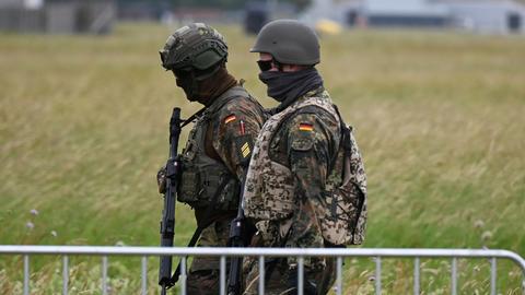 Soldaten der Bundeswehr gehen am Luftwaffenstützpunkt der Bundeswehr in Jagel durch hohes Gras.