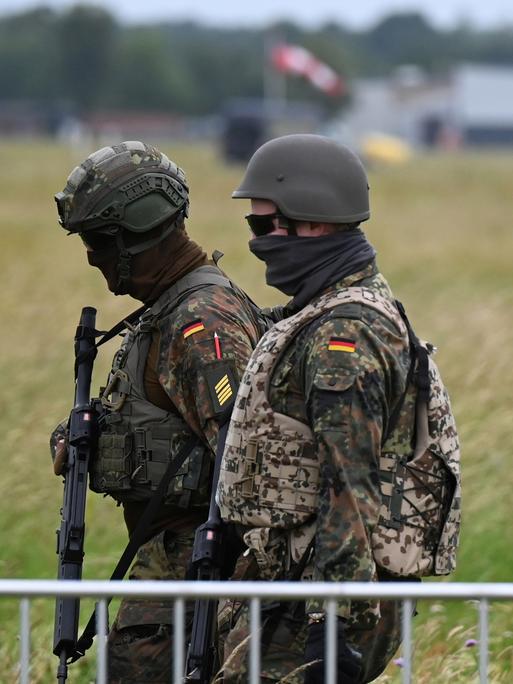 Soldaten der Bundeswehr gehen am Luftwaffenstützpunkt der Bundeswehr in Jagel durch hohes Gras.