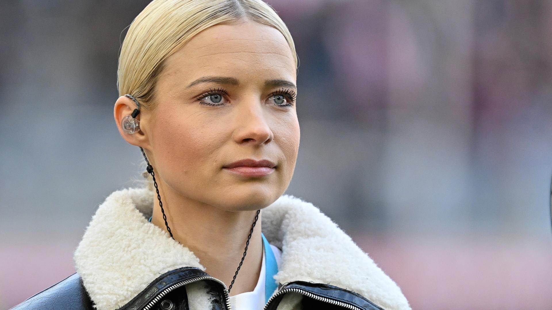 Moderatorin Lena Cassel mit In-Ear.Kopfhörern auf dem Fußballplatz Moderatorin Lena Cassel mit In-Ear.Kopfhörern auf dem Fußballplatz