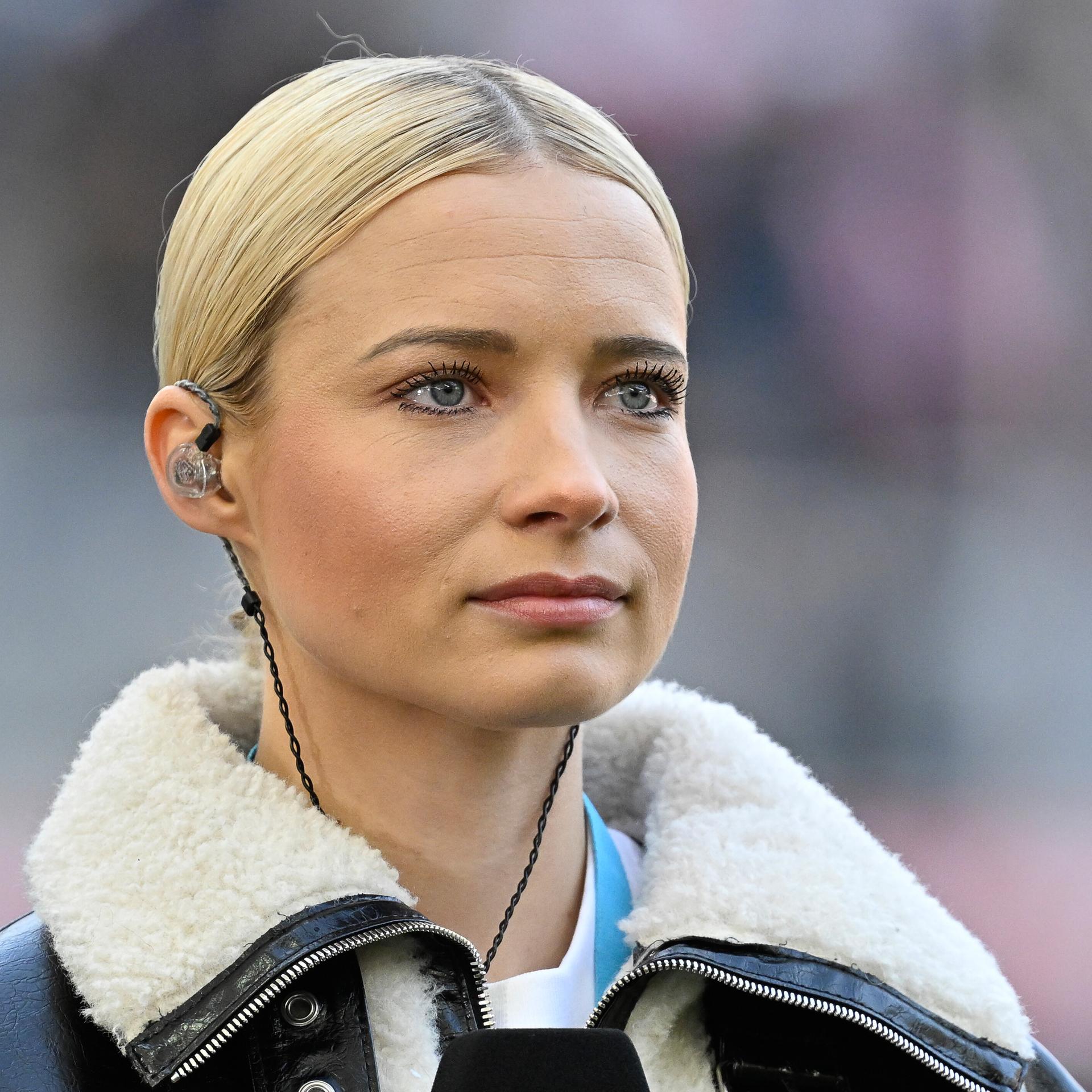 Moderatorin Lena Cassel mit In-Ear.Kopfhörern auf dem Fußballplatz