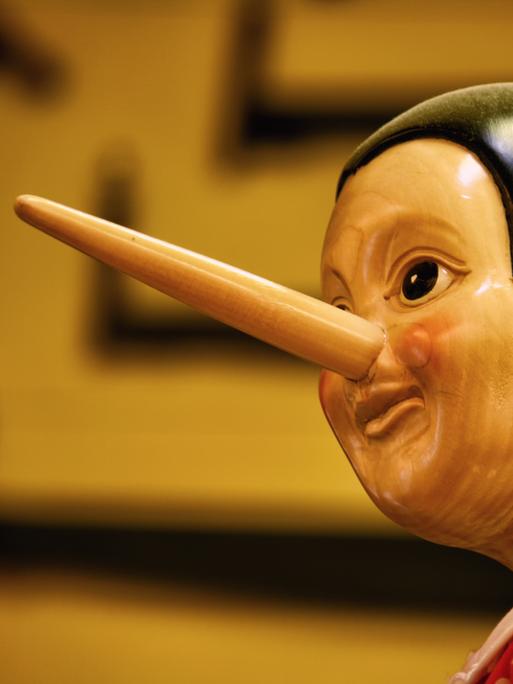 Ein hölzerner Pinocchio vor braunem Hintergrund.