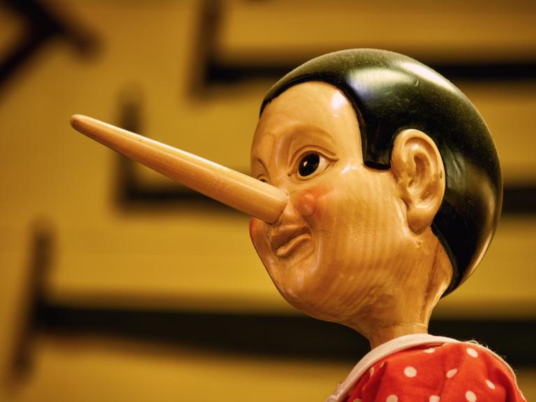 Ein hölzerner Pinocchio vor braunem Hintergrund.