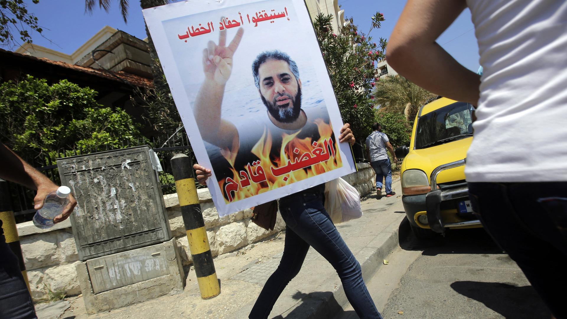 Ein Anhänger des Salafistenpredigers Scheich al-Assir im Libanon trägt ein Plakat mit dem Foto des Sängers Fadel Shaker