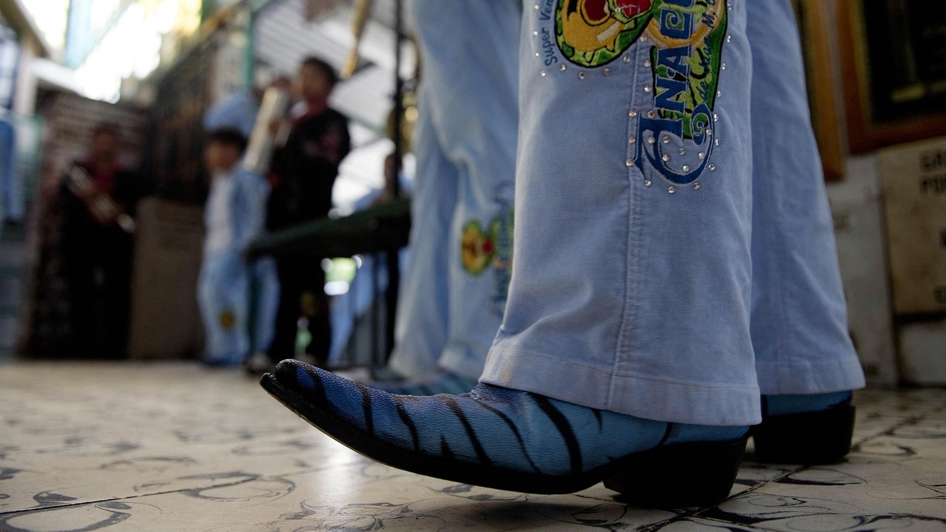 Ein Besucher eines Narcocorridos-Konzerts in Jeans und auffälligen Cowboy-Stiefeln. Ein Besucher eines Narcocorridos-Konzerts in Jeans und auffälligen Cowboy-Stiefeln.