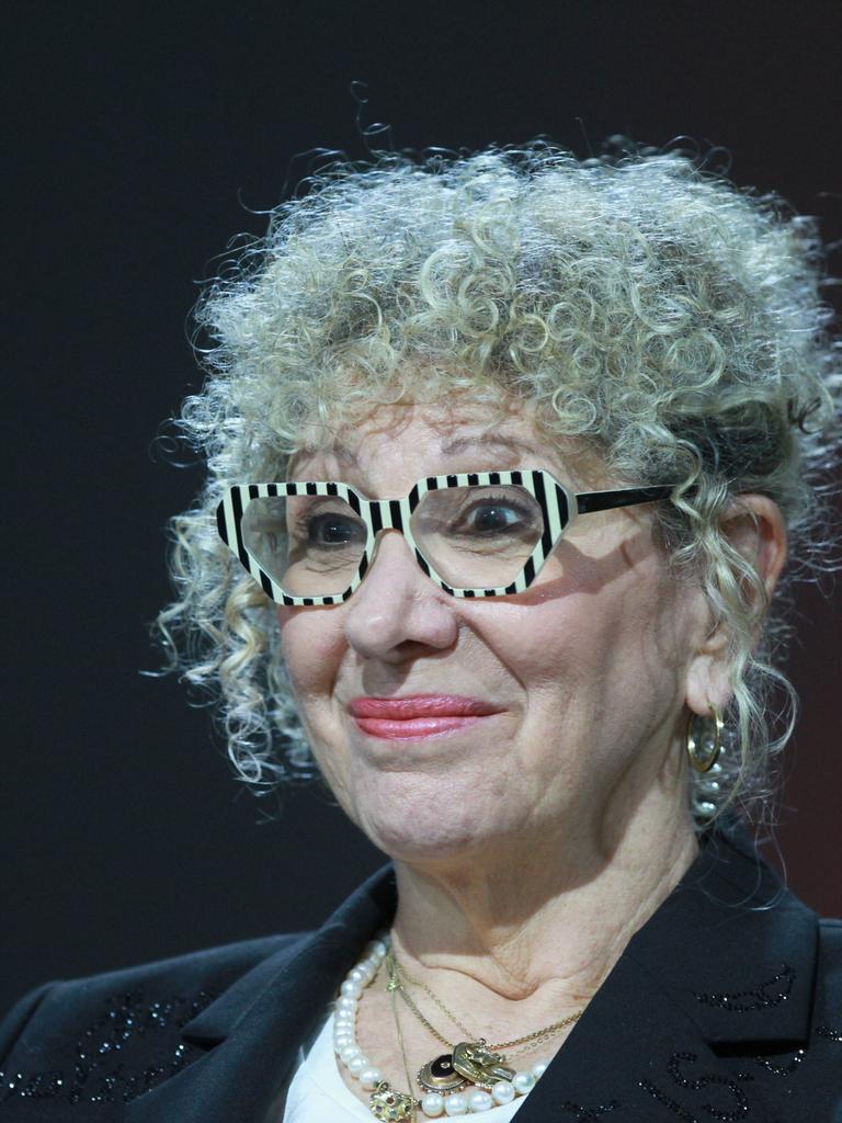 Ein Foto der Schriftstellerin Lizzie Doron aufgenommen am 21.10.2023 auf der Frankfurter Buchmesse. Sie sitzt vor einem schwarzen Hintergrund, wahrscheinlich einer Bühne, hat ein leichtes Lächeln auf den Lippen und trägt eine auffällige Brille.