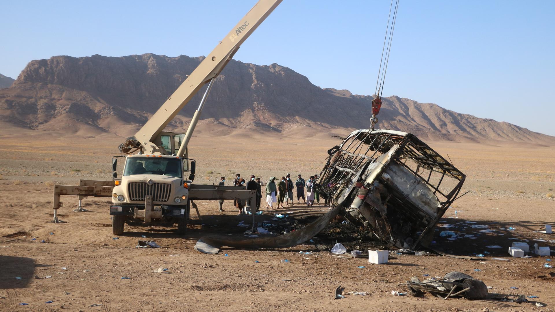 Ein Kran hebt die Überreste eines ausgebrannten Passagierbusses nach einem Verkehrsunfall in der westafghanischen Provinz Herat.