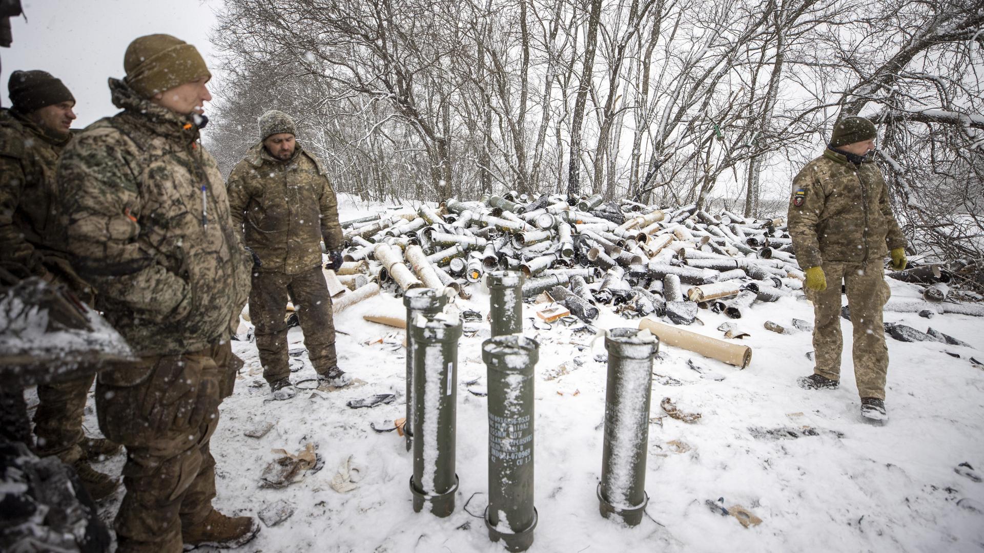 Ukrainische Soldaten stehen neben einer amerikanischen Panzerhaubitze und einem Berg an verbrauchter Munition