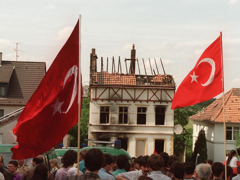 Demonstranten tragen am 29. Mai 1993 vor dem ausgebrannten Haus der Familie Genç in Solingen türkische Fahnen. 