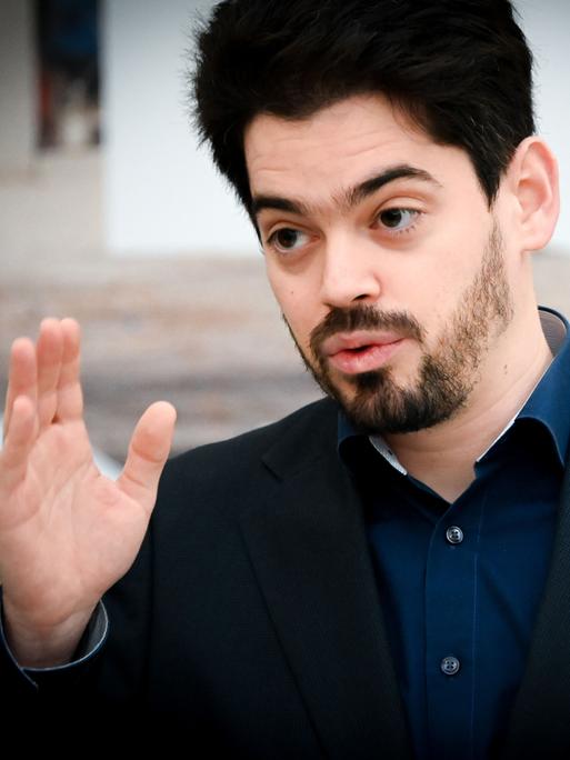 Der Dirigent Lahav Shani erhebt mit ernster Miene seine Hand.