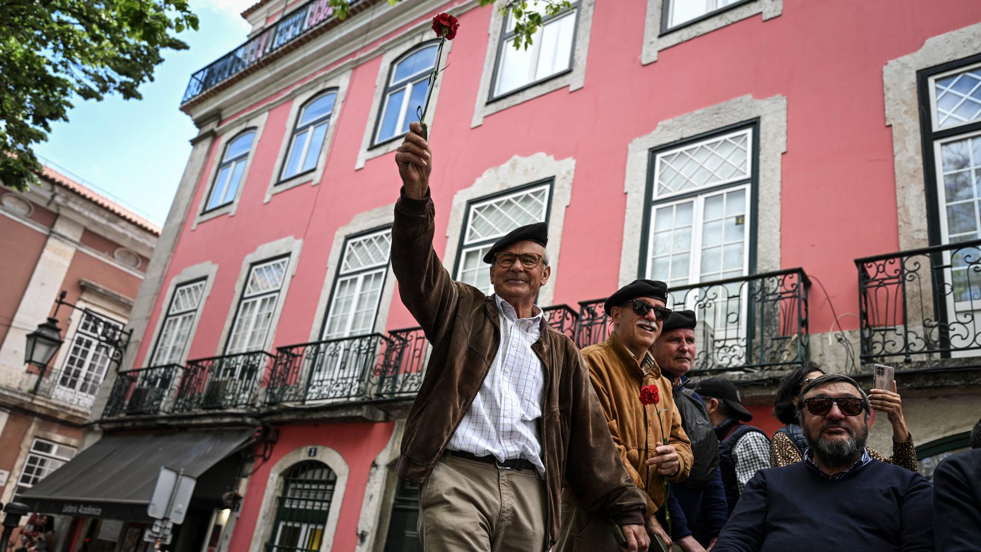 Ein Mann nimmt an einer Militärparade zu Gedenken der Nelkenrevolution teil. Er hält eine rote Nelke in der Hand.