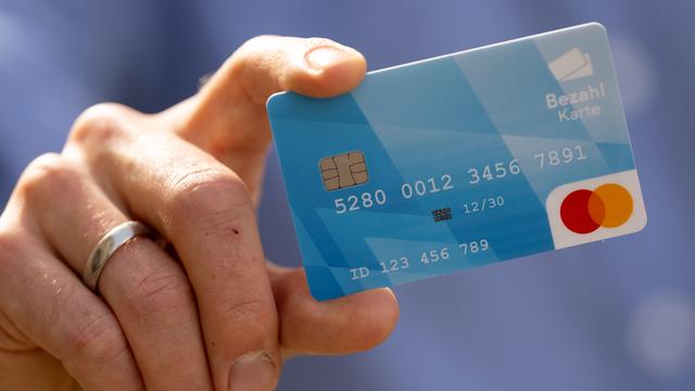 München: Ein Mann hält während einer Pressekonferenz eine Bezahlkarte in der Hand.