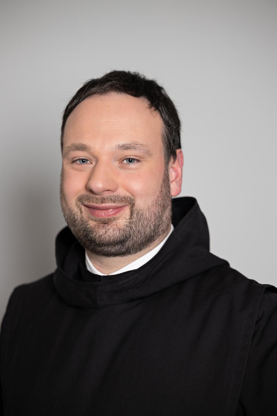 Pater Nikodemus Schnabel trägt eine schwarze Kutte und lächelt freundlich in die Kamera