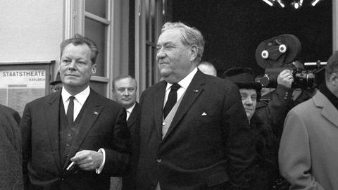 SPD-Parteivorsitzender Willy Brandt (l) und der führende SPD-Politiker Carlo Schmid (M) am Ende einer Gedenkfeier zu Beginn des SPD-Parteitags am 22.11.1964 in Karlsruhe.