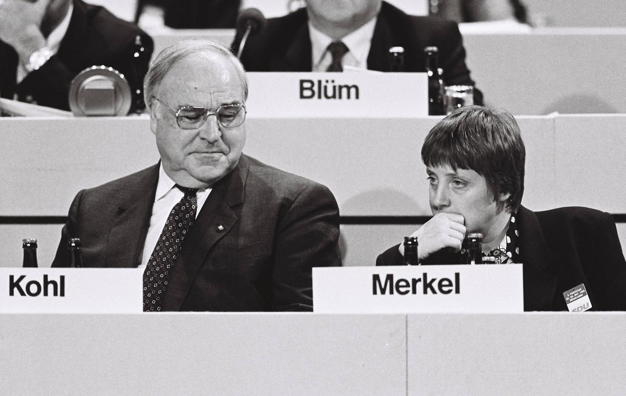 Helmut Kohl und Angela Merkel sitzen nebeneinander, Kohl lächelt