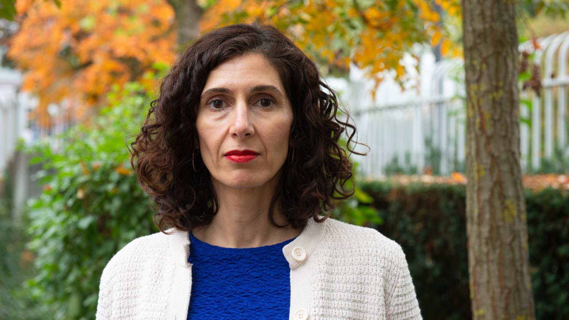 Nava Ebrahimi steht in einem herbstlichen Park und schaut in die Kamera.