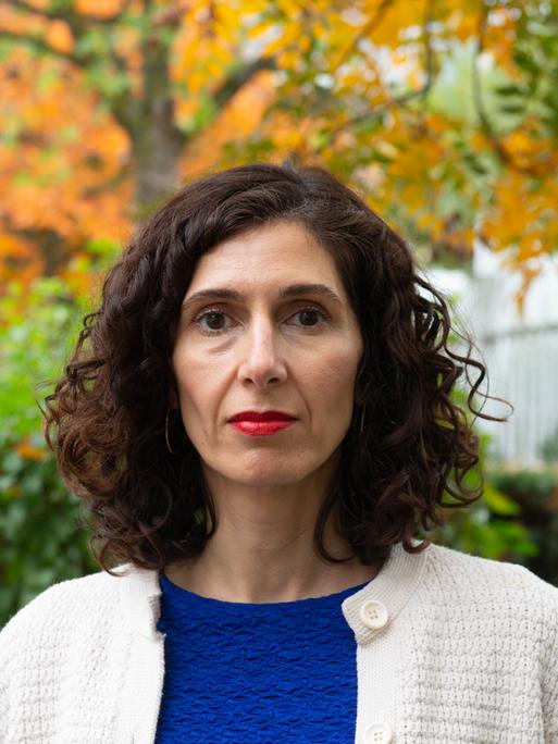 Nava Ebrahimi steht in einem herbstlichen Park und schaut in die Kamera.