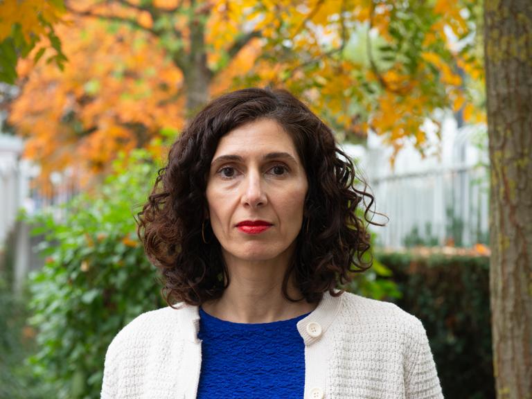 Nava Ebrahimi steht in einem herbstlichen Park und schaut in die Kamera.