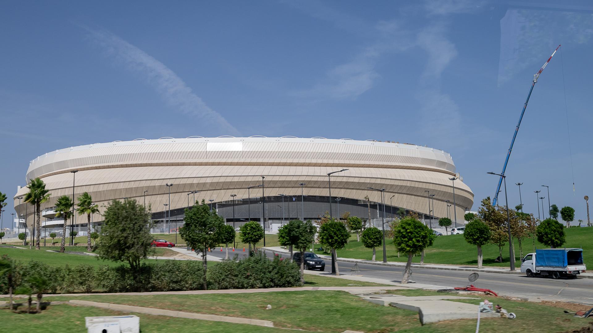 Das Fußballstadion von Tanger, welches bereits für die Weltmeisterschaft 2030 renoviert wird, ist ein helles Stadiongebäude umgeben von Rasen und Bäumen.