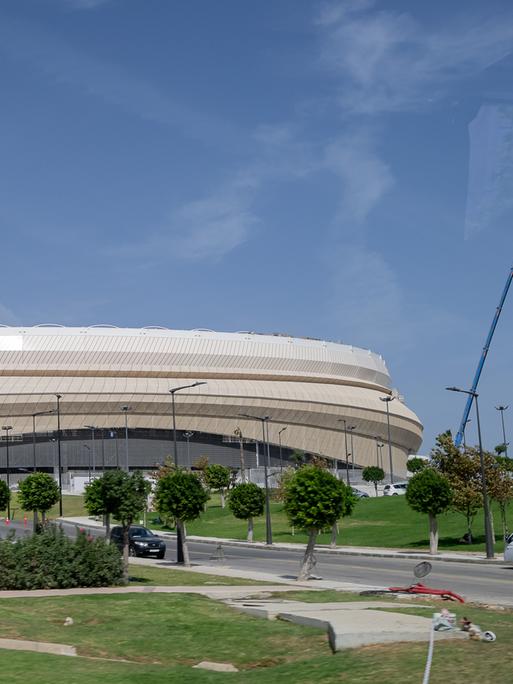 Das Fußballstadion von Tanger, welches bereits für die Weltmeisterschaft 2030 renoviert wird, ist ein helles Stadiongebäude umgeben von Rasen und Bäumen.