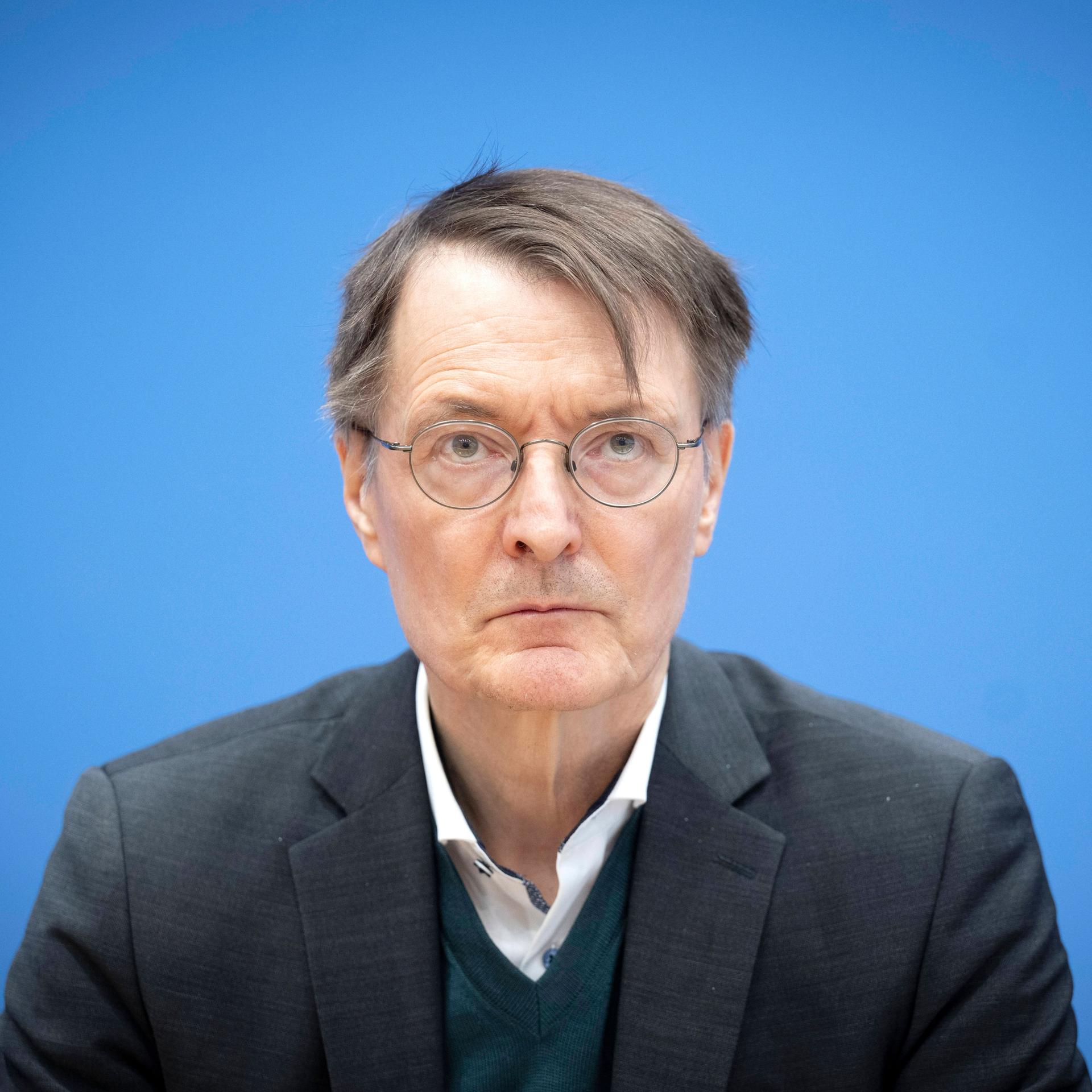 Bundesgesundheitsminister Karl Lauterbach während eines Termins in der Bundespressekonferenz vor blauem Hintergrund.