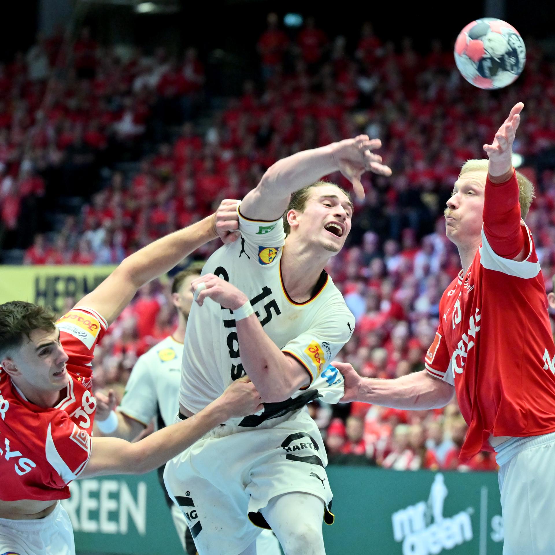 Das Bild zeigt ein Gerangel bei einem Handball-Spiel während eines Torwurfs.