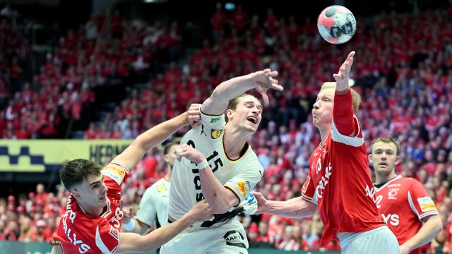 Das Bild zeigt ein Gerangel bei einem Handball-Spiel während eines Tor-Wurfs.