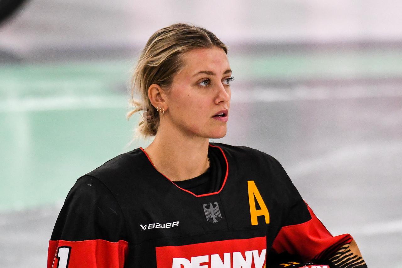 Die deutsche Eishockey-Nationalspielerin Nicola Eisenschmid schaut auf das Spielfeld. Sie trägt das deutsche Nationaltritkot, aber keinen Helm. 