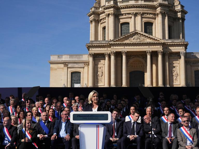 Marine Le Pen ist eine französische Politikerin der rechtspopulistischen bis rechtsextremen Partei Rassemblement National (RN), deren Vorsitz sie bis 2022 hatte. Sie spricht vor dem Invalidendom in Paris bei einer Demo gegen ihre Verurteilung.