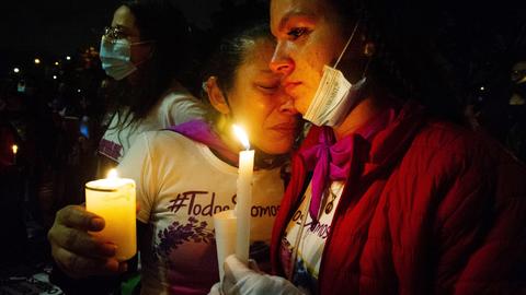 Die Mutter eines Opfers weint auf einem Protest gegen Femizide in Bogota, Kolumbien. Die Frauen halten Kerzen und trösten sich gegenseitig. 25.11.2021.