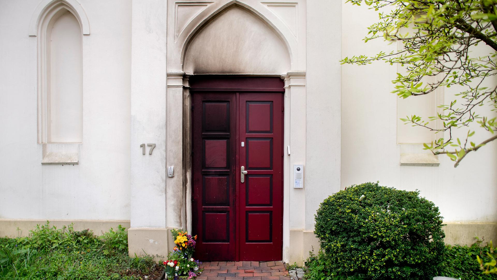 Zahlreiche Blumen liegen vor der rußgeschwärzten Tür der Oldenburger Synagoge.