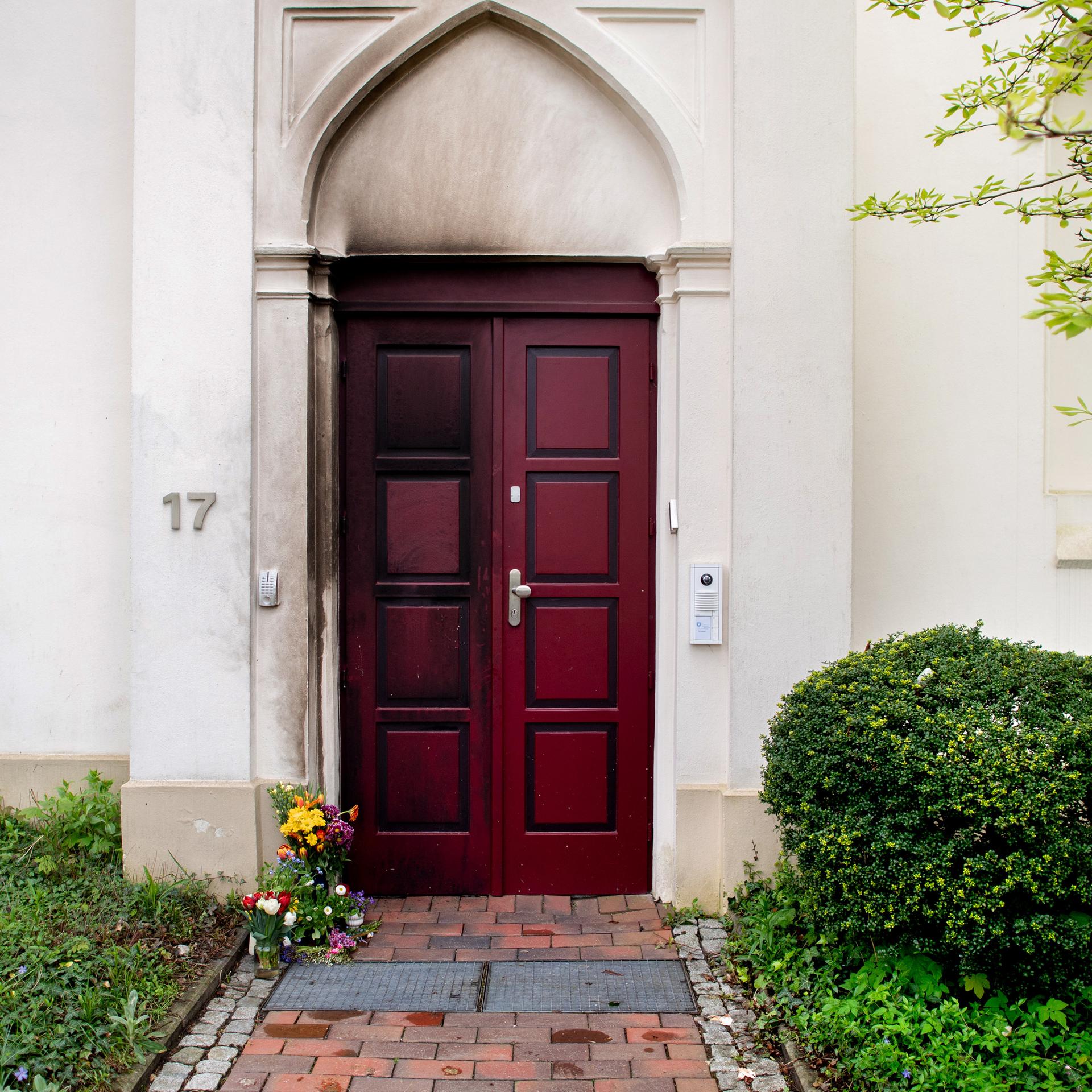 Zahlreiche Blumen liegen vor der rußgeschwärzten Tür der Oldenburger Synagoge.