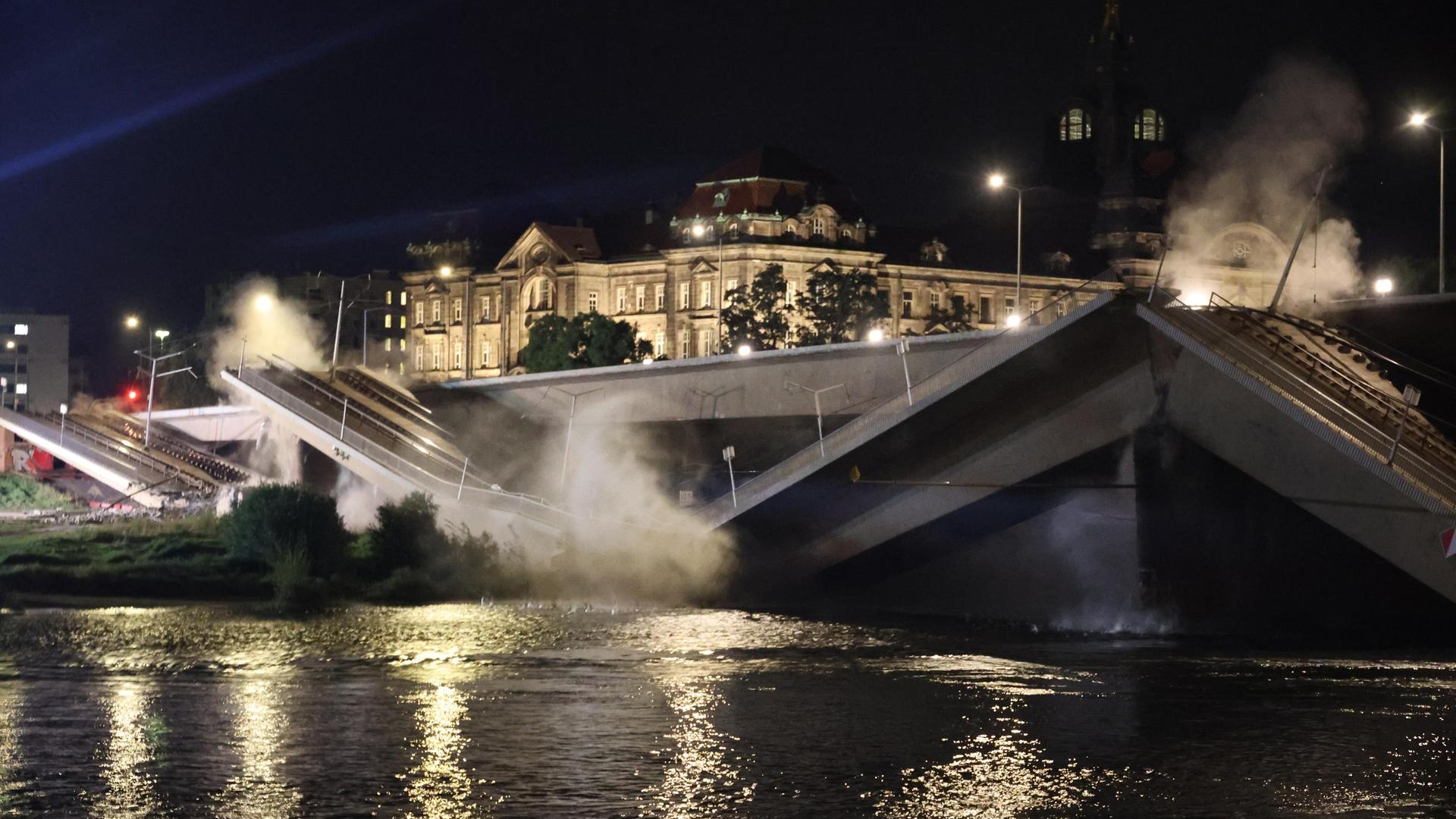 Qualm steigt über eingestürzten Teilen einer Brücke nach einer kontrollierten Sprengung auf.