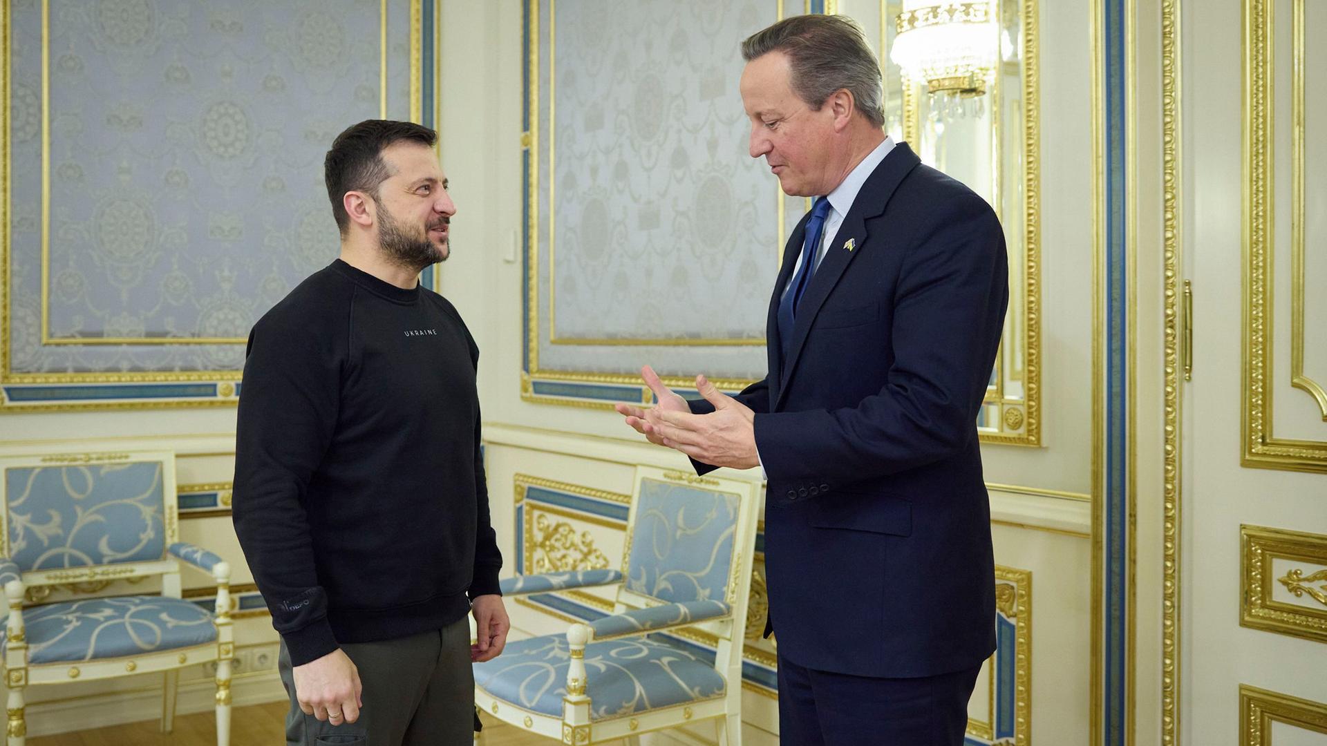 Der neue britische Außenminister und der Präsident der Ukraine, Selenskyj, stehen sich gegenüber und unterhalten sich.