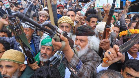Sehr agitierte Anhänger der Huthi-Rebellen erheben ihre Waffen und führen drohende Gesten aus