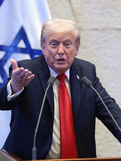 US-Präsident Trump steht in der Knesset hinter zwei Mikrofonen, hinter ihm die israelische Fahne