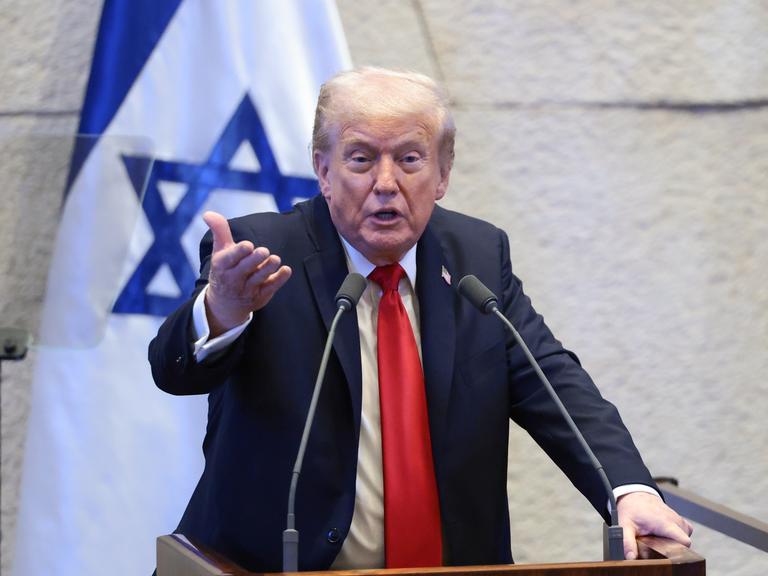 US-Präsident Trump steht in der Knesset hinter zwei Mikrofonen, hinter ihm die israelische Fahne