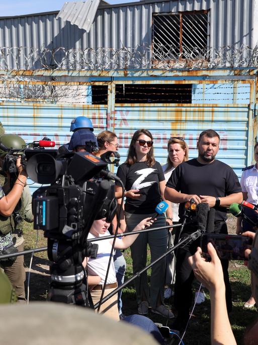 Denis Pushilin, the leader of the Donetsk People's Republic, background second right, speaks to foreign journalists at the destroyed barrack by following a strike on a prison housing POWs in Olenivka during a trip organized by the Russian Ministry of Defense, on the territory which is under the Government of the Donetsk People's Republic control, eastern Ukraine, Wednesday, Aug. 10, 2022. Russia has claimed that Ukraine's military used U.S.-supplied rocket launchers to strike the prison in Olenivka, a settlement controlled by the Moscow-backed Donetsk People's Republic. The Ukrainian military denied making any rocket or artillery strikes in Olenivka. (AP Photo)
