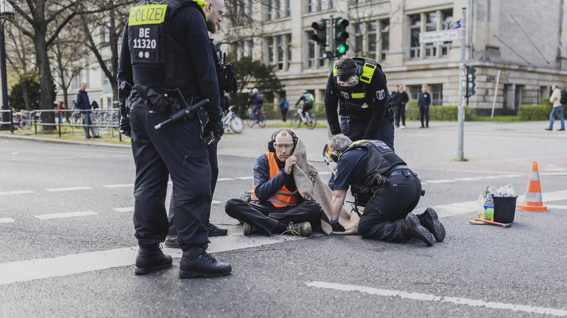 Ein Aktivist wird von der Polizei nach einer Klebeaktion aus der Strasse am Ernst-Reuter-Platz in Berlin geschnitten