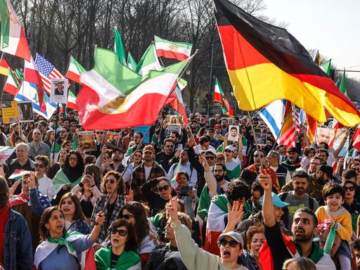 Das Foto zeigt eine Menschenmenge, die iranische, deutsche, US-amerikanische und israelische Flaggen schwenkt und gegen das iranische Regime protestiert. Die Demonstration fand am 7. März 2026 in Berlin statt. Das Foto zeigt eine Menschenmenge, die iranische, deutsche, US-amerikanische und israelische Flaggen schwenkt und gegen das iranische Regime protestiert. Die Demonstration fand am 7. März 2026 in Berlin statt.