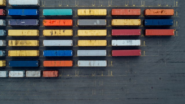 Das Bild zeigt mehrere Frachtcontainer aus der Vogelperspektive. Darauf steht in weißer Schrift „Dlf Doku“