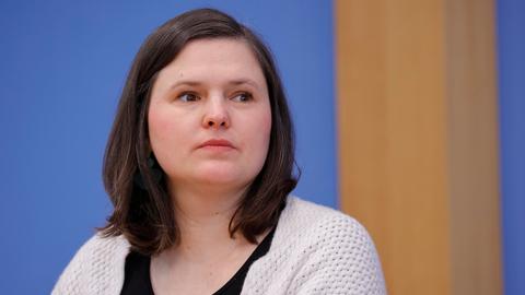 Sara Nanni trägt eine beige Strickjacke über einem schwarzen T-Shirt und schaut nachdenklich und mit ernstem Blick aus dem Bild heraus.