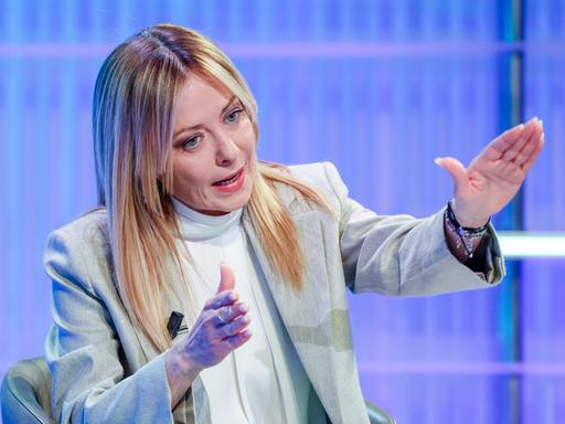 Giorgia Meloni sitzt in einem TV-Studio und gestikuliert während des Sprechens