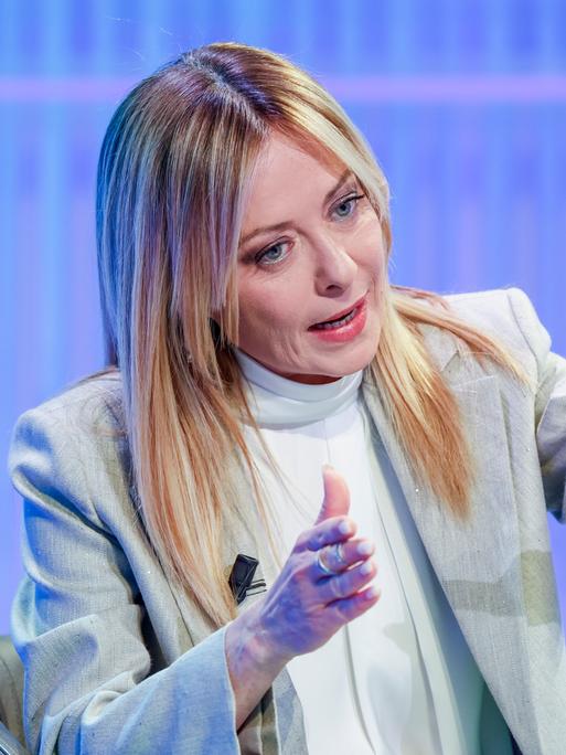 Giorgia Meloni sitzt in einem TV-Studio und gestikuliert während des Sprechens
