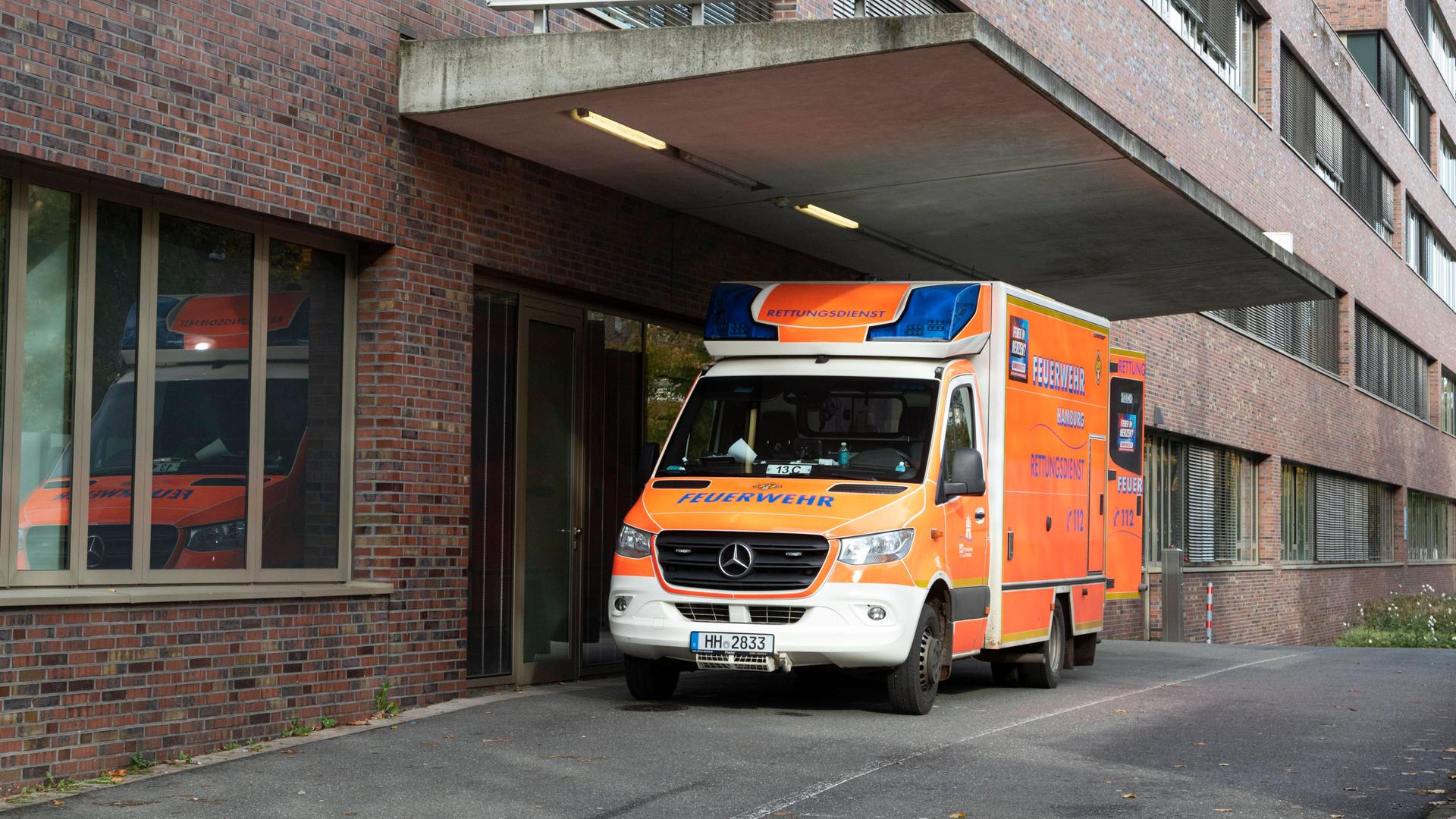Ein Krankenwagen steht vor einem Krankenhaus. An dem backsteinernen Gebäude ist ein Schriftzug mit dem Wort "Notaufnahme" befestigt.