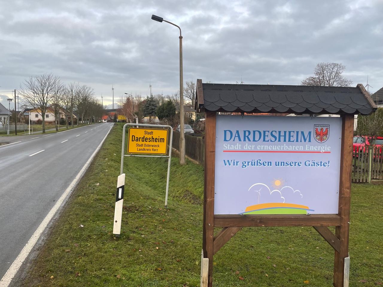 Neben dem Ortsschild von Dardesheim steht eine Hinweistafel mit der Aufschrift "Dardesheim - Stadt der erneuerbaren Energien. Wir grüßen unsere Gäste"